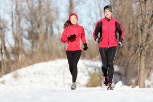 Sport couple running in winter. Runners jogging in snow in city